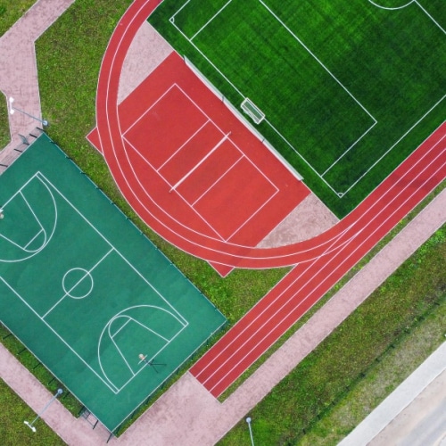An outdoor sports field with a track, a soccer field, and basketball courts.