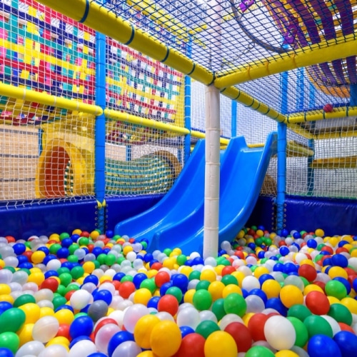 Indoor children's playground with a slide, nets, and a ball pit.